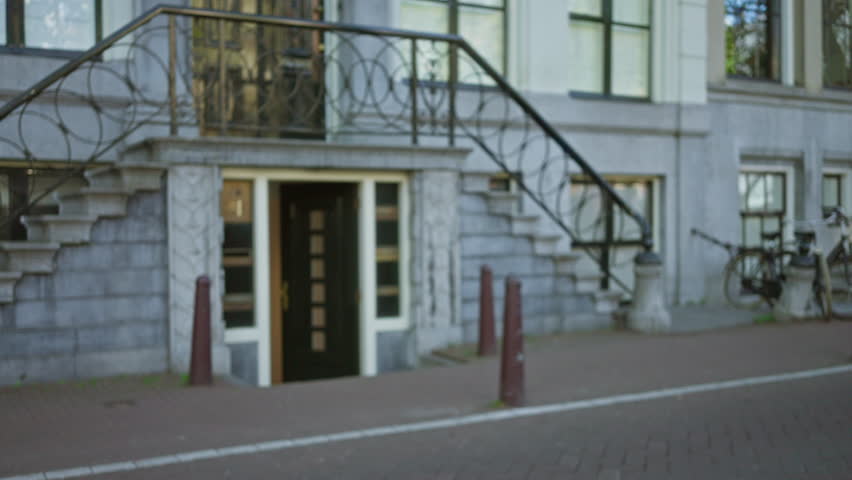 Blurry european town scene with defocused staircase leading to a black door surrounded by bicycles and cobblestones, evoking a classic outdoor city vibe.