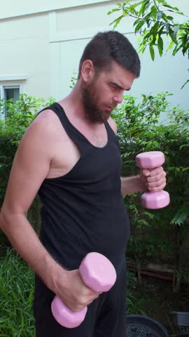 Out-of-shape man lifting dumbbells with exaggerated effort