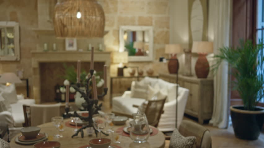 Cozy indoor living room with blurry decor accents and a rustic wooden table set for dining under warm lighting, showcasing a serene, stylish atmosphere.