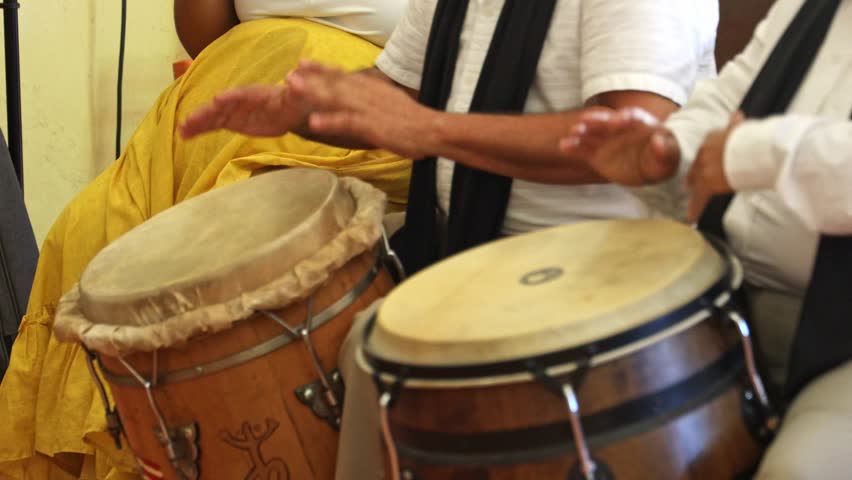 A closeup footage of two people playing congas at the church in Loiza, Puerto Rico