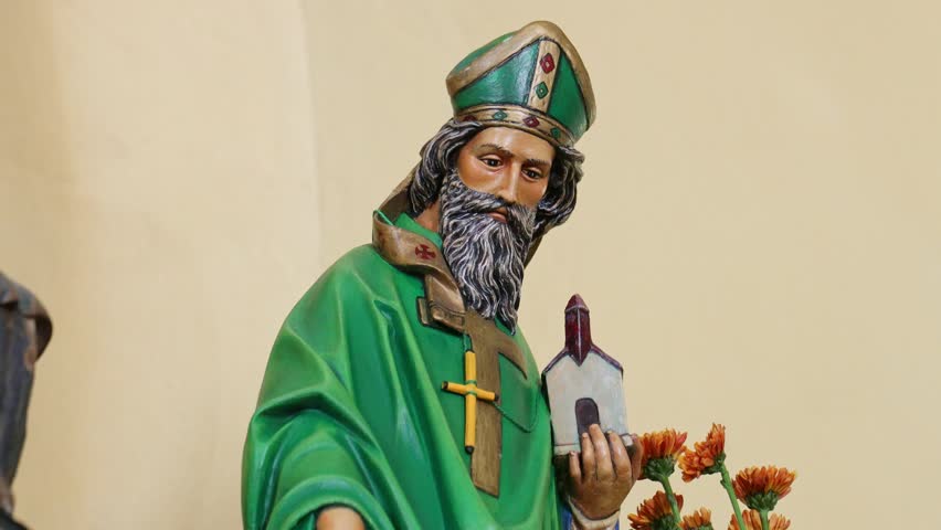 A Religious figure of bearded man holding chapel, standing against blank wall inside church in Loiza, Puerto Rico
