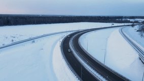 An aerial view of a highway and a bridge traversing a snow covered winter landscape under a bright sunset sky - Powered by Shutterstock - Get 15% off with code: PIKWIZARD15