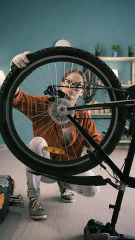 Brunette woman repairing bicycle at home spinning bicycle wheel checking tire
