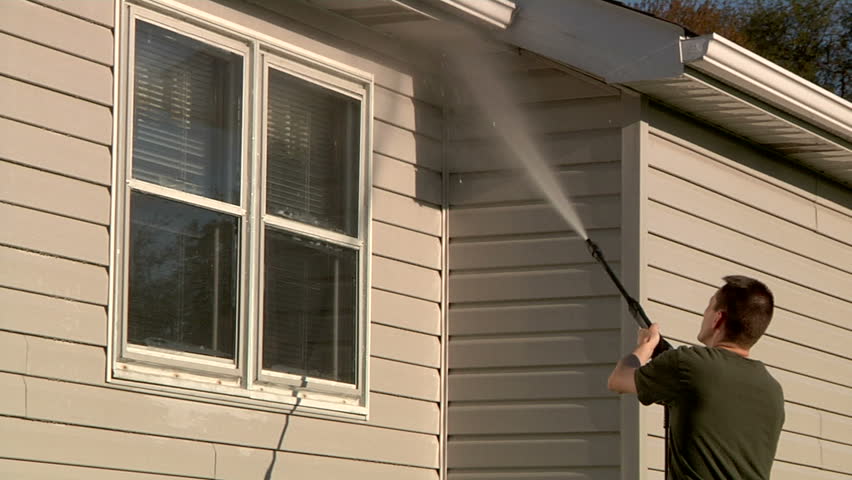 A man power washes the outside of his house.