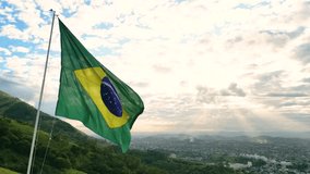 Large Brazilian Flag Waving in the Sky With Nova Iguacu City in the Horizon and the Sun Shining Through Clouds - Powered by Shutterstock - Get 15% off with code: PIKWIZARD15