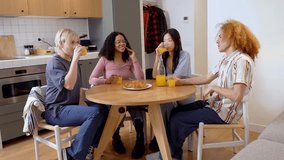 Four diverse friends share breakfast, laughter, and engaging conversation around a kitchen table - Powered by Shutterstock - Get 15% off with code: PIKWIZARD15