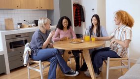 Four diverse friends sharing breakfast, drinking orange juice, and chatting together at a kitchen table - Powered by Shutterstock - Get 15% off with code: PIKWIZARD15