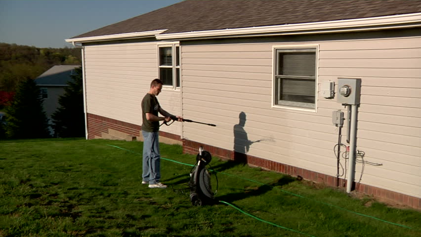 A man power washes the outside of his house.