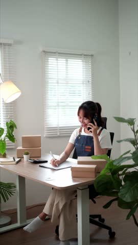 Focused entrepreneur balancing customer communication and product packing tasks in green calm workspace setup
