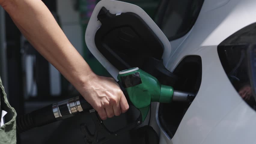 Woman refueling her car at a gas station - fuel and oil crisis concept