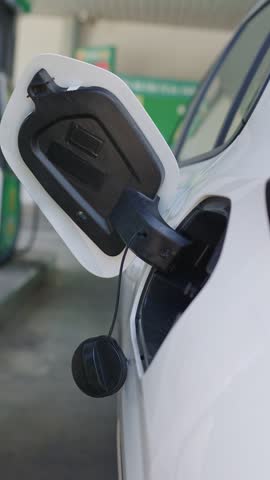 Driver fueling white car at gas station - fuel and oil crisis concept