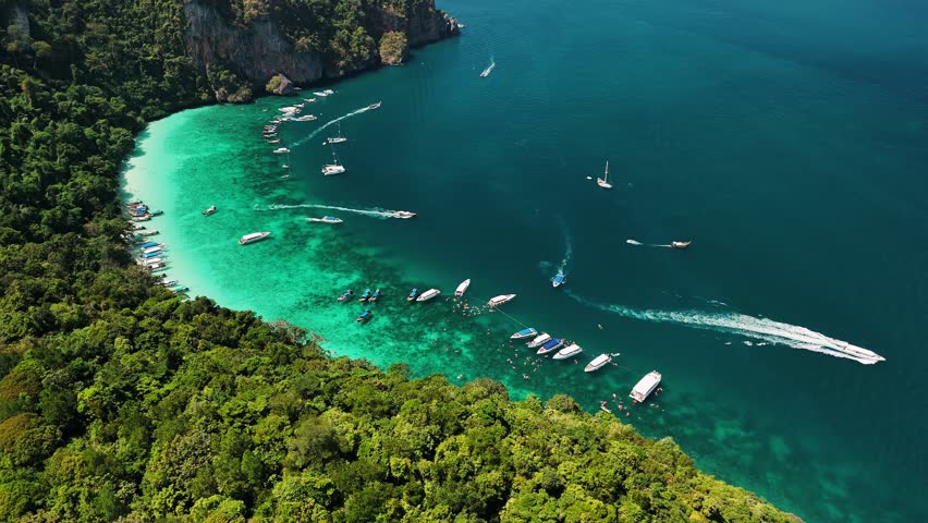 Turquoise water and white sand beach at Maya Bay, with boats and tourists enjoying the beautiful landscape, Phi phi island, Thailand