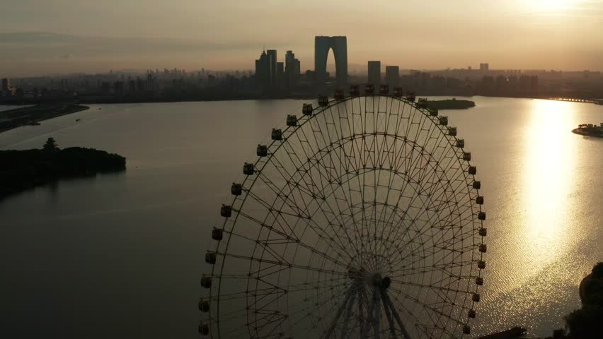 Aerial view of Jinji Lake Ferris Wheel in Suzhou during sunset, capturing the beauty of the city skyline and shimmering water