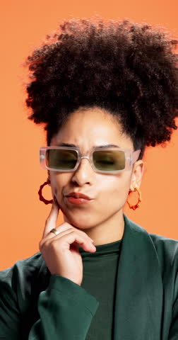 Thinking, sunglasses and woman in studio, decision and stylish outfit on orange background. Person, shades and model with choice, contemplation and problem solving with solution, wonder and planning