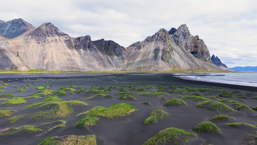 Majestic Coastal Landscape featuring Mountains and Expansive, Lush Green Dyunes Nearby. Stokksnes. Iceland