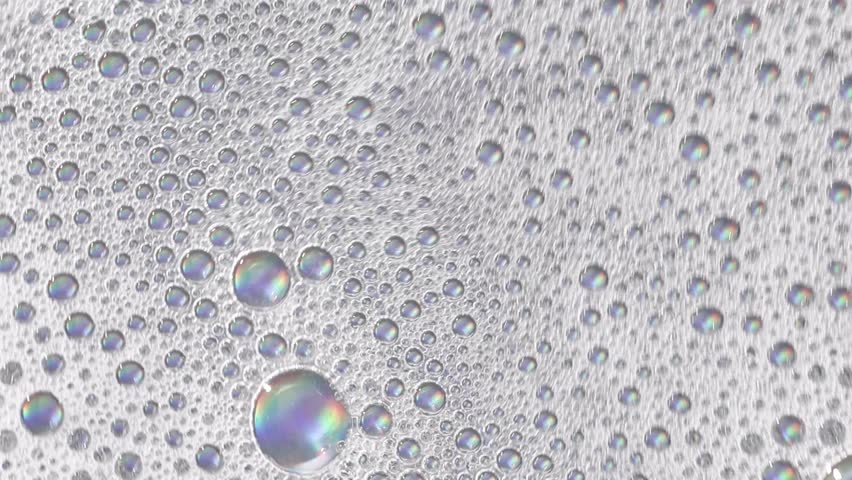 Foam background. Liquid soap bubbles, Froth bubbles backdrop. Soap foam popping bubble rotating, white backdrop. Soap sud macro structure close-up. Clean, cleaning, washing, laundry
