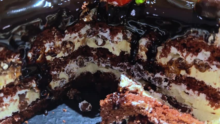 Chocolate cake with strawberries. Close-up of cake with slice removed. Cake slice texture. Chocolate cake cut as textured background. Macro shot. Pastry background. 