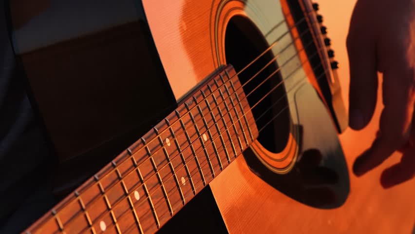 Close-up of Acoustic Guitar Playing in Warm Lighting