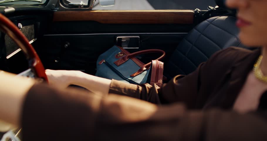 A woman drives a retro car. Close-up of her bag in the passenger seat