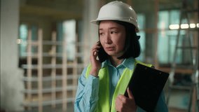Asian woman builder architect Chinese engineer master technician electrician girl Korean Japanese female inspector industrial worker in hard hat displeased talking mobile phone indoors building work - Powered by Shutterstock - Get 15% off with code: PIKWIZARD15
