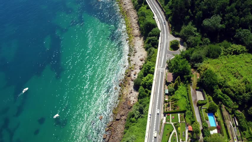 Cars driving on the scenic coastal road of getaria, gipuzkoa, basque country, spain, during a sunny summer day