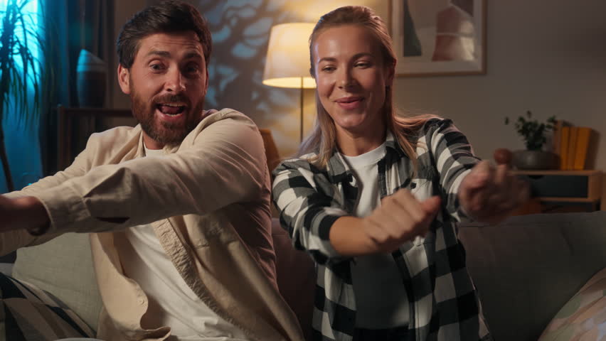 Funny Caucasian couple happy family husband wife girl guy dancing together on sofa couch have fun carefree woman man spouses dance move celebrate moving day holiday evening night relax at home party
