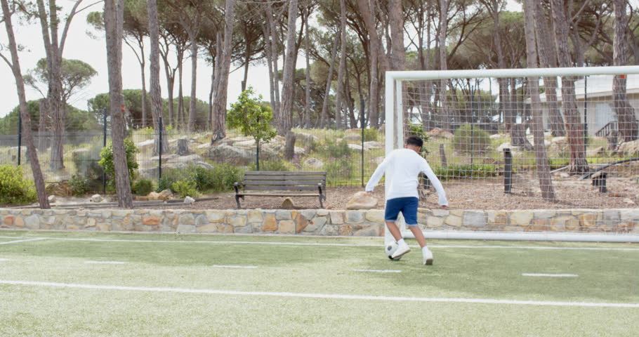 Boy playing soccer on field, dribbling ball near goal in park, copy space. sports, football, athlete, competition, teamwork, outdoor