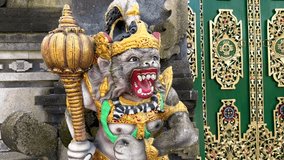 Vivid close-up of colorful Hanuman statue guarding temple entrance in Bali, Indonesia. Hindu monkey deity with golden crown and mace stands in front of ornate green temple doors. - Powered by Shutterstock - Get 15% off with code: PIKWIZARD15