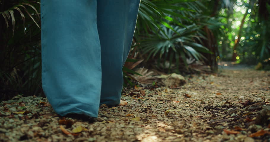 Female feet step softly on forest trail with dry leaves near a cenote in Mexico