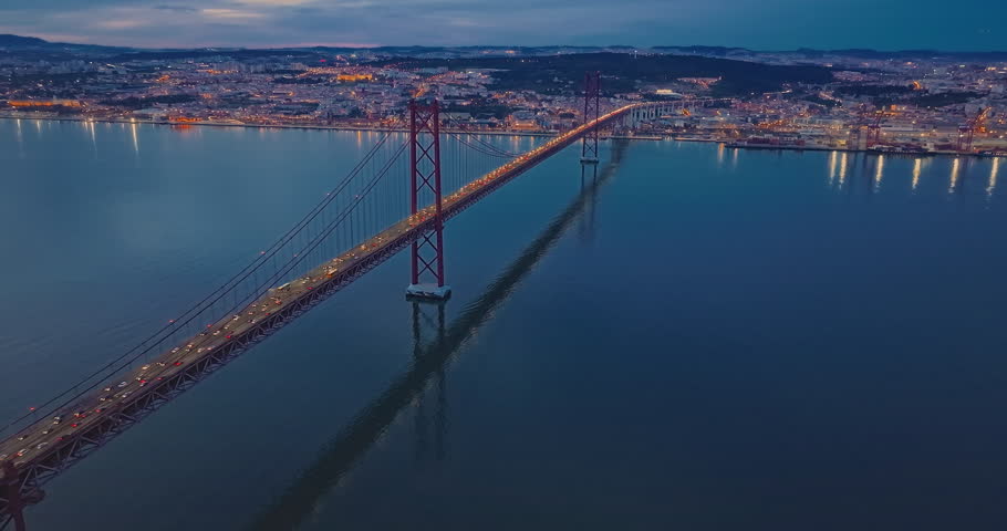 Aerial view of cars driving on bridge in night time. Suspension bridge over Tagus river in Lisbon. Portugal