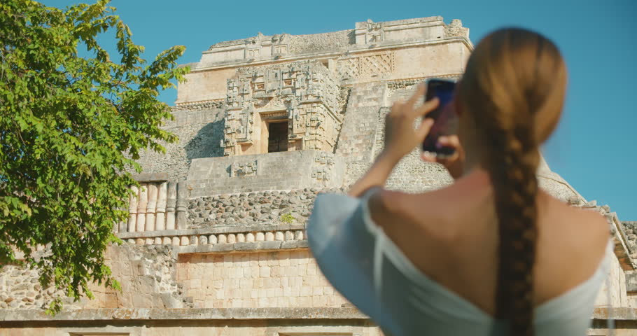 Close-up of woman photographing ancient Mayan ruins architecture in Mexico