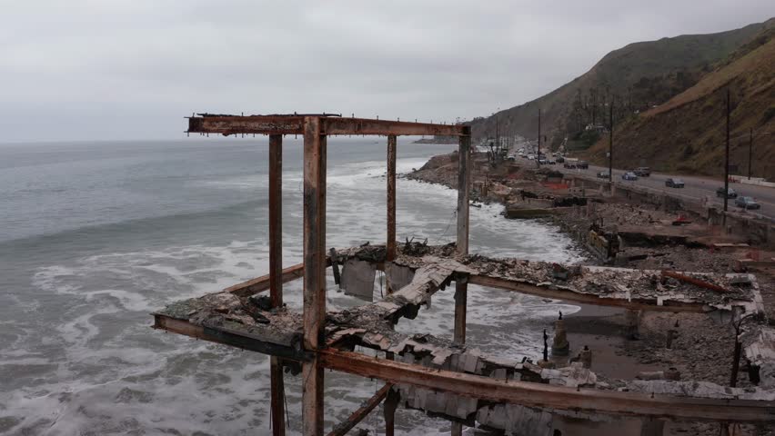 Close-up panning aerial shot of the remains of a burned home along Pacific Coast Highway after the Palisades Fire in Los Angeles, California. 4K
