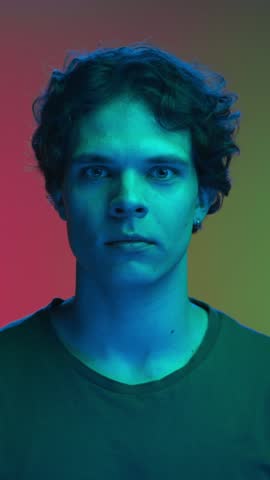 Happy Portrait of Young Man Looking at Camera and Smiling in Neon UV Color of Filter. Shine Effect of Ultraviolet Light and Backlight Illumination Inside Amazing Studio. Trendy Person with Toothy Grin