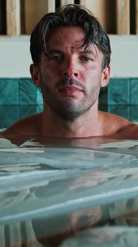 Attractive Man Dives into Cold Water of Swimming Pool with Ice Cubes for Body Health. Healthy Person in Bathtub Full of Chilled Liquid for Youth Therapy. Rehab Routine of Naked Sportsman in Large Bath