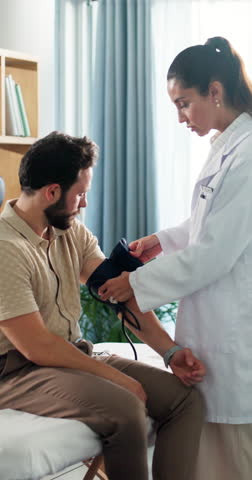 Doctor, man and exam with blood pressure at clinic, assessment and check for hypertension. Woman, medical equipment and consulting with patient, test and monitor with healthcare services at hospital