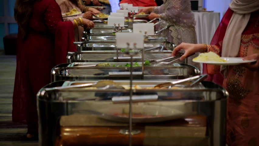 Ladies enjoying the catering buffet with variety of dishes at venue on event. 