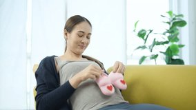 Happy pregnant woman lying on sofa and holding pink baby shoes on belly, expressing joy and love during maternity, symbolizing anticipation and bonding between mother and unborn baby at home. - Powered by Shutterstock - Get 15% off with code: PIKWIZARD15