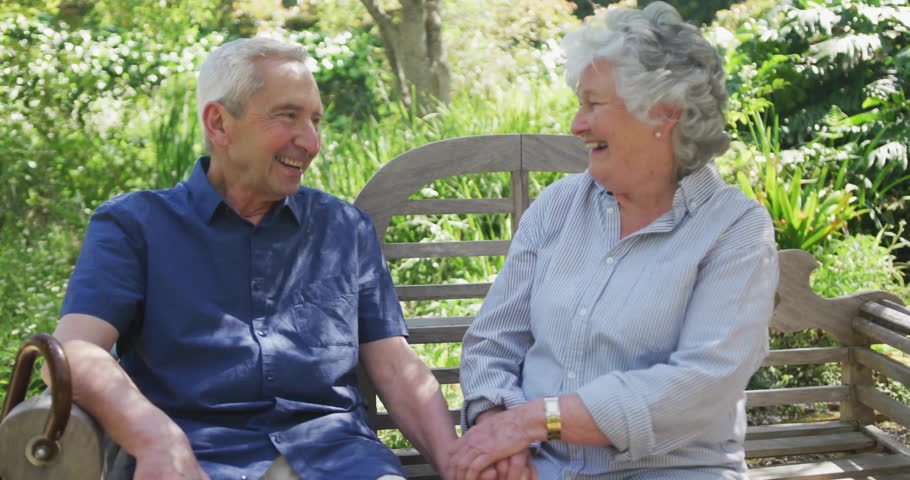 Senior couple chatting on bench, starting chat bubbles floating around faces then fading for health. Senior, companionship, outdoor, serenity, communication, leisure, tranquility