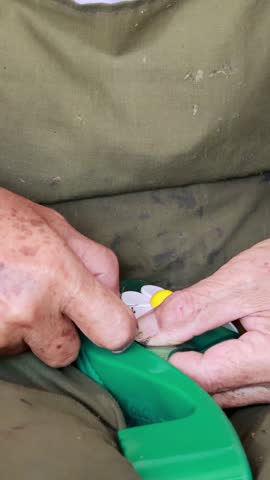Close-up of skilled hands stitching a green shoe with floral design, showcasing traditional craftsmanship