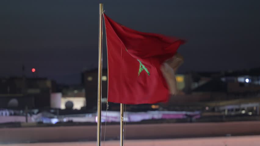 Moroccan flag waving in the wind near restaurants at Jemaa el-Fnaa in the Old Town Medina area of Marrakech, west Morocco 