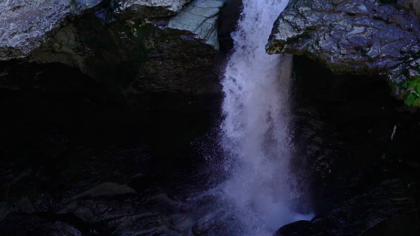 Panning shot going up from a waterfall into the river and the forests