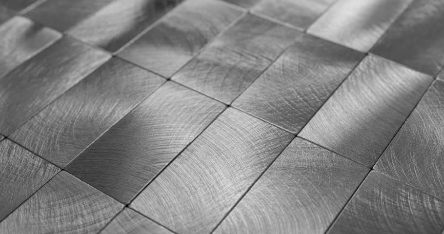 Polished Metal Tile Surface Close-Up. Video showcasing a sleek, textured arrangement of polished metal tiles, reflecting light with a modern industrial aesthetic.