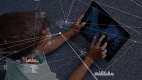 Boy lying on gray carpet tapping tablet screen for viewing network data with pulsing graphics. Technology, innovation, digital, youth, interaction, futuristic, entertainment - Powered by Shutterstock - Get 15% off with code: PIKWIZARD15