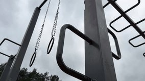 Metal monkey bars and gym rings on an outdoor playground against a dramatic cloudy sky – minimalist urban workout structure, low-angle view - Powered by Shutterstock - Get 15% off with code: PIKWIZARD15