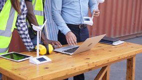 Engineer worker team discussing of solar energy from wind turbine model and laptop at construction site. diversity people brainstorming and working together - Powered by Shutterstock - Get 15% off with code: PIKWIZARD15
