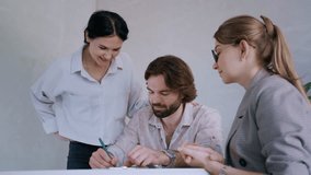 A man signs a mortgage contract while his wife and real estate agent watch, capturing a key moment in the home buying process - Powered by Shutterstock - Get 15% off with code: PIKWIZARD15