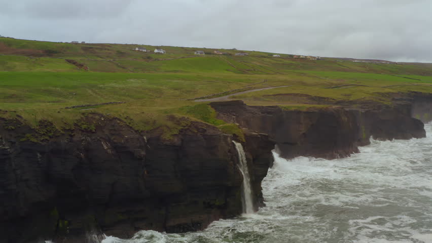 Close aerial view of Cliffs of Moher waterfall at Doolin plunging into Atlantic Ocean