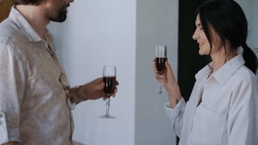Standing in their new apartment, a cheerful couple raises glasses, clinks them, and kisses - Powered by Shutterstock - Get 15% off with code: PIKWIZARD15