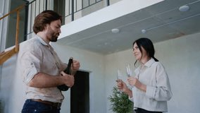 A joyful couple opens a bottle of champagne in their newly bought two-level apartment, celebrating the successful purchase of their dream home - Powered by Shutterstock - Get 15% off with code: PIKWIZARD15