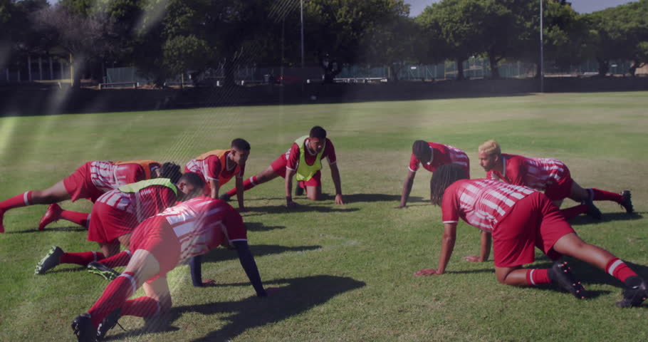 Seven soccer players dropping into push-up stance after neon-bib leader signal on pitch for fitness. Athletic, teamwork, outdoor, training, motivation, strength, fitness